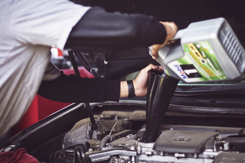 Mechanic performing an oil change on a vehicle in a service bay